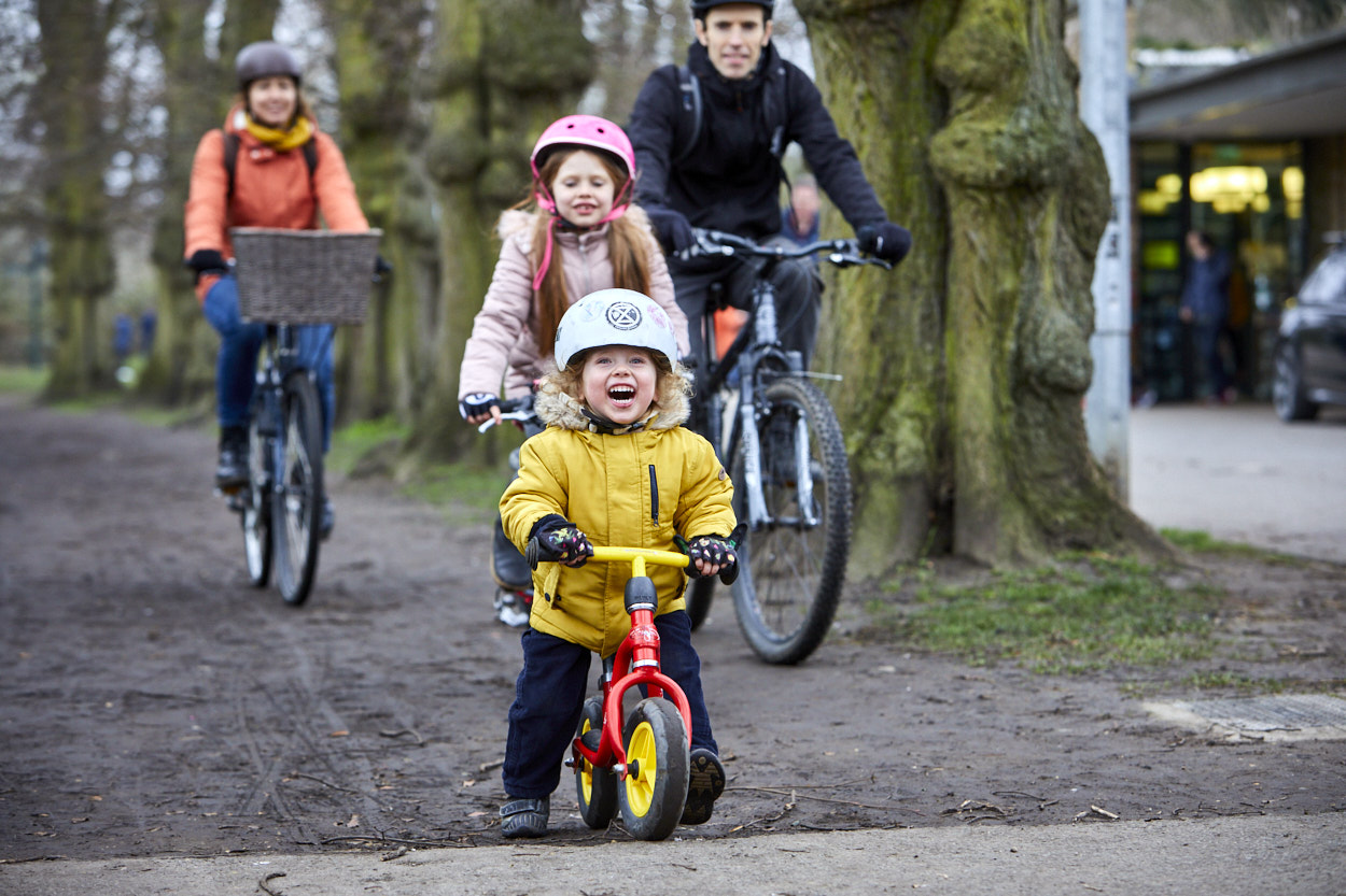 Small child on balance bike with their family