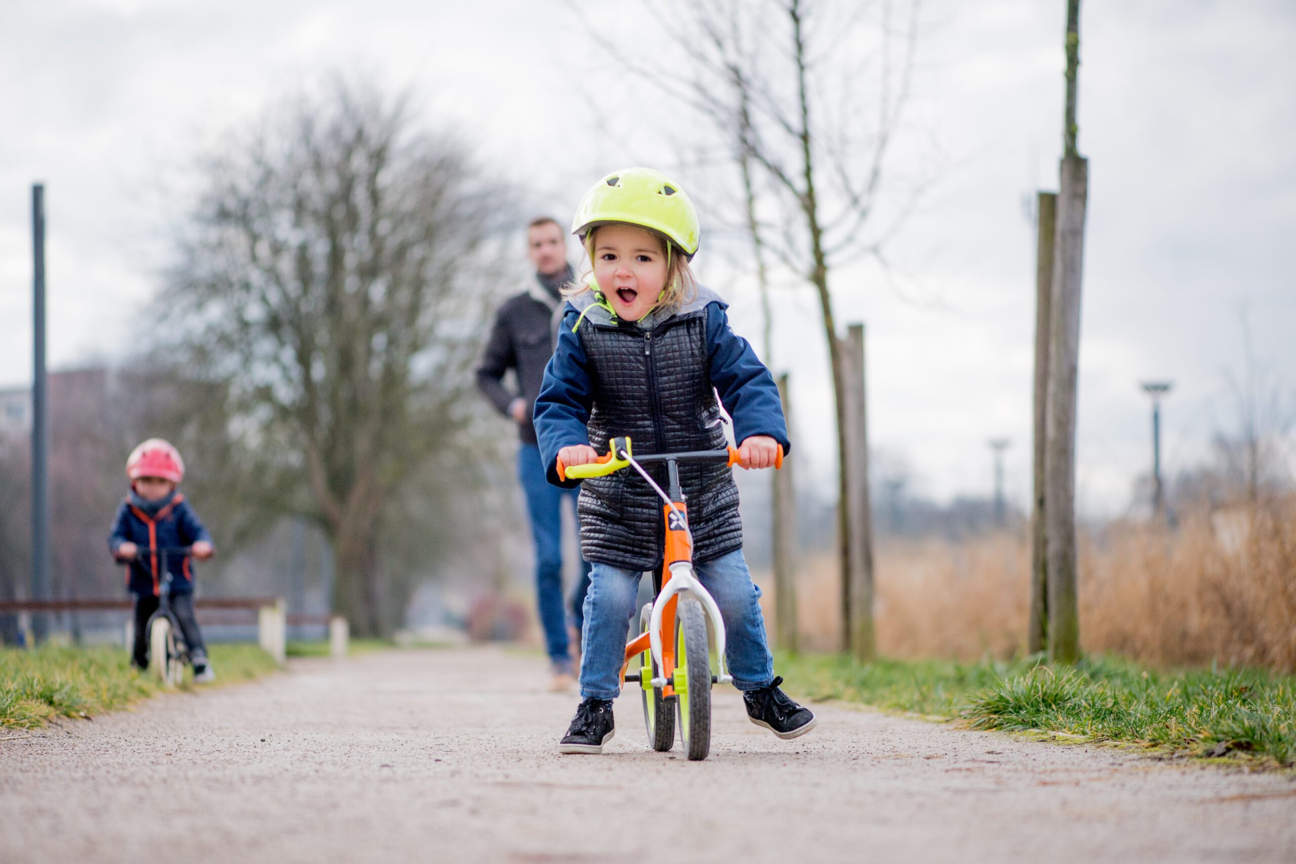 A child in a helmet riding balance bike in a park