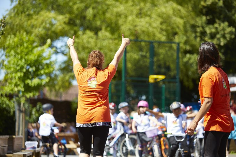 A Bikeability instructor with her back to the camera doing two thumbs up in the air