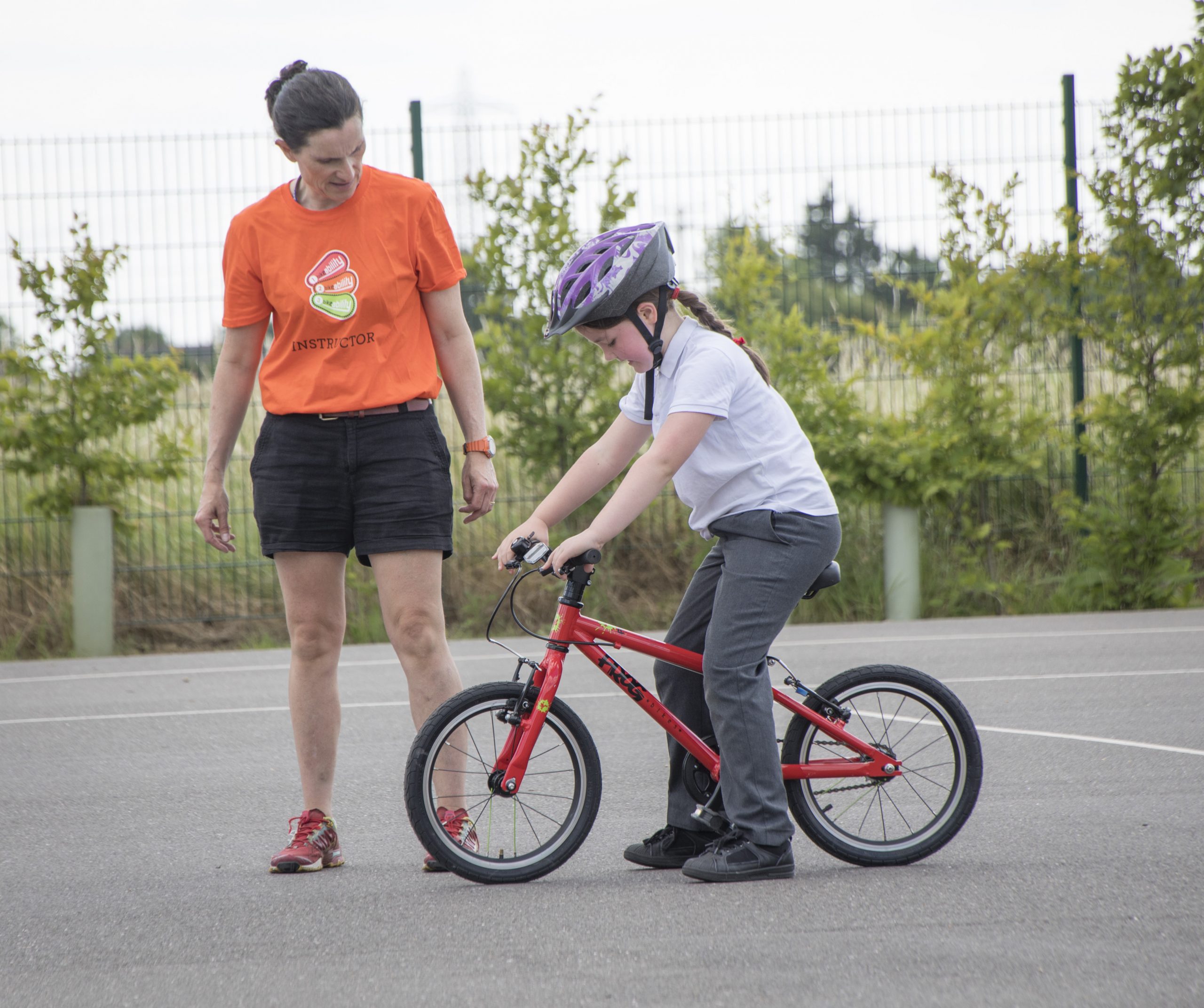 A female Bikeability instructor with a young girl on a bike