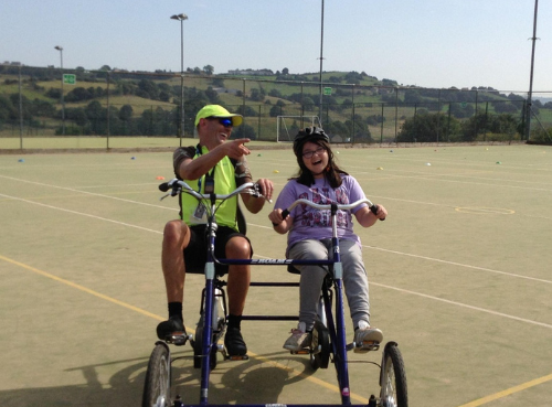 A Bikeability instructor on a side by side bike with a child