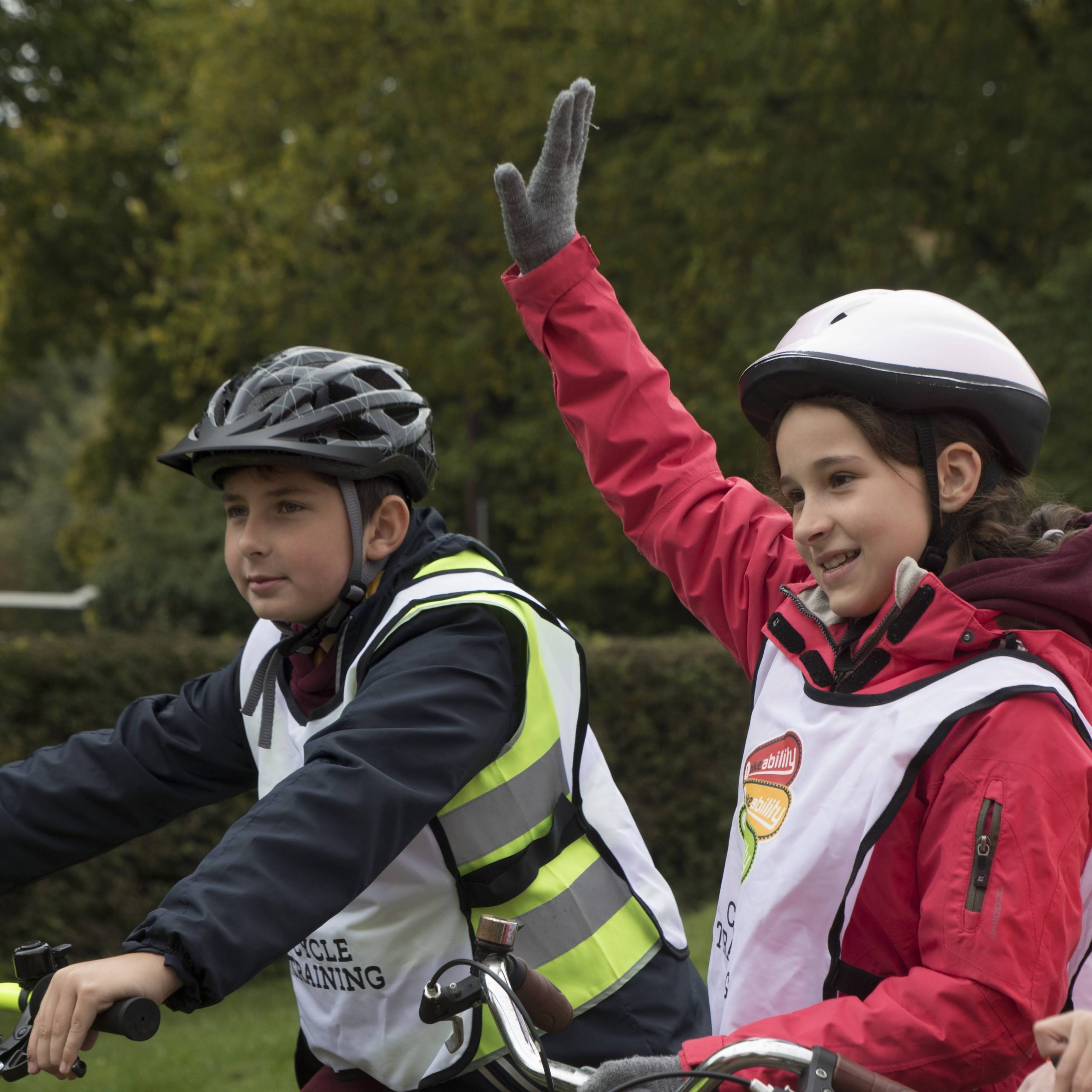 A boy and a girl wearing helmets on bikes during a Bikeability session.