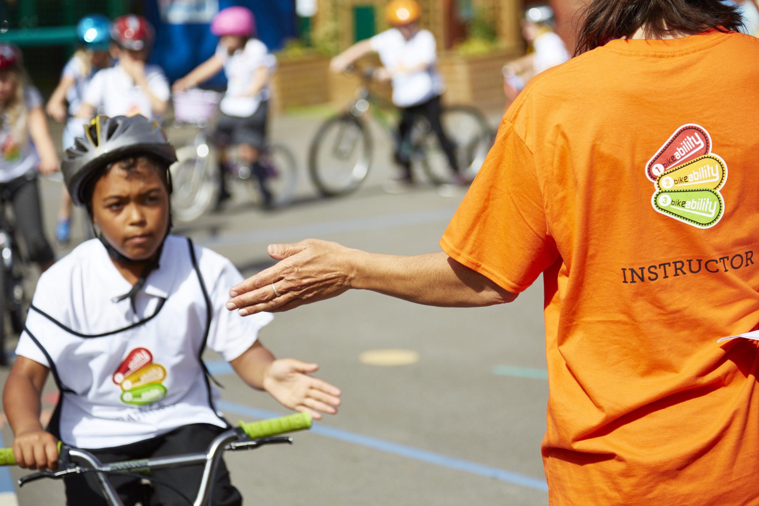 A young boy high fives a Bikeability instructor