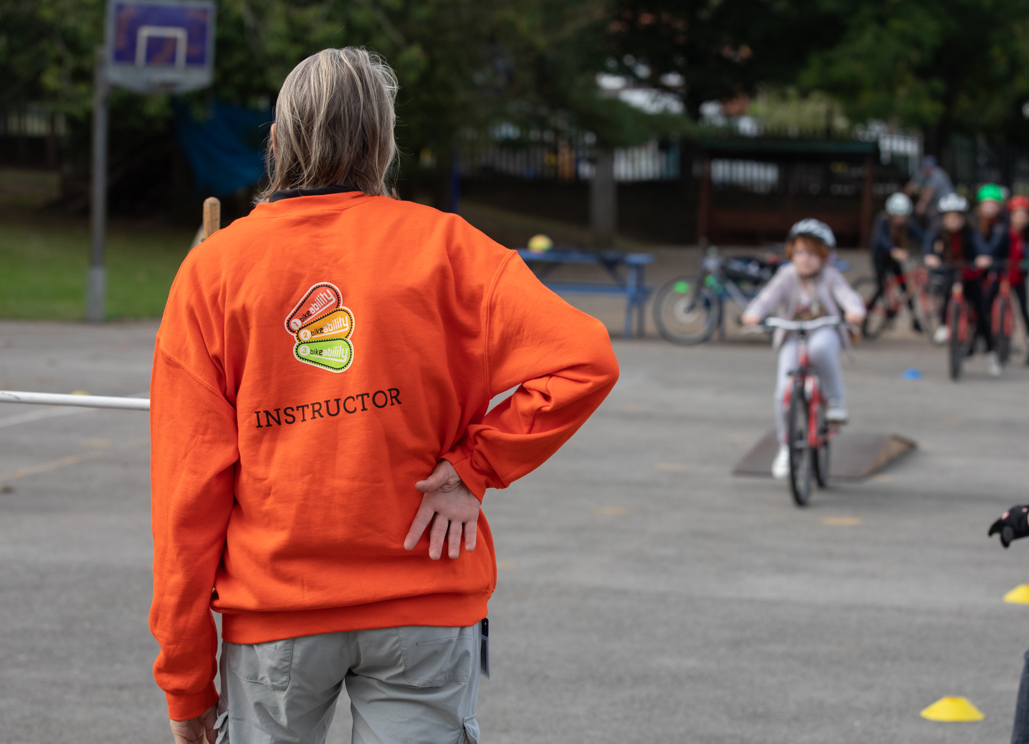 An instructor stands watching a student cycle