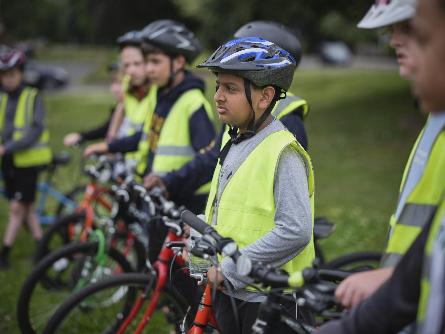 Children in hi-vis and bike helmets standing with their bikes