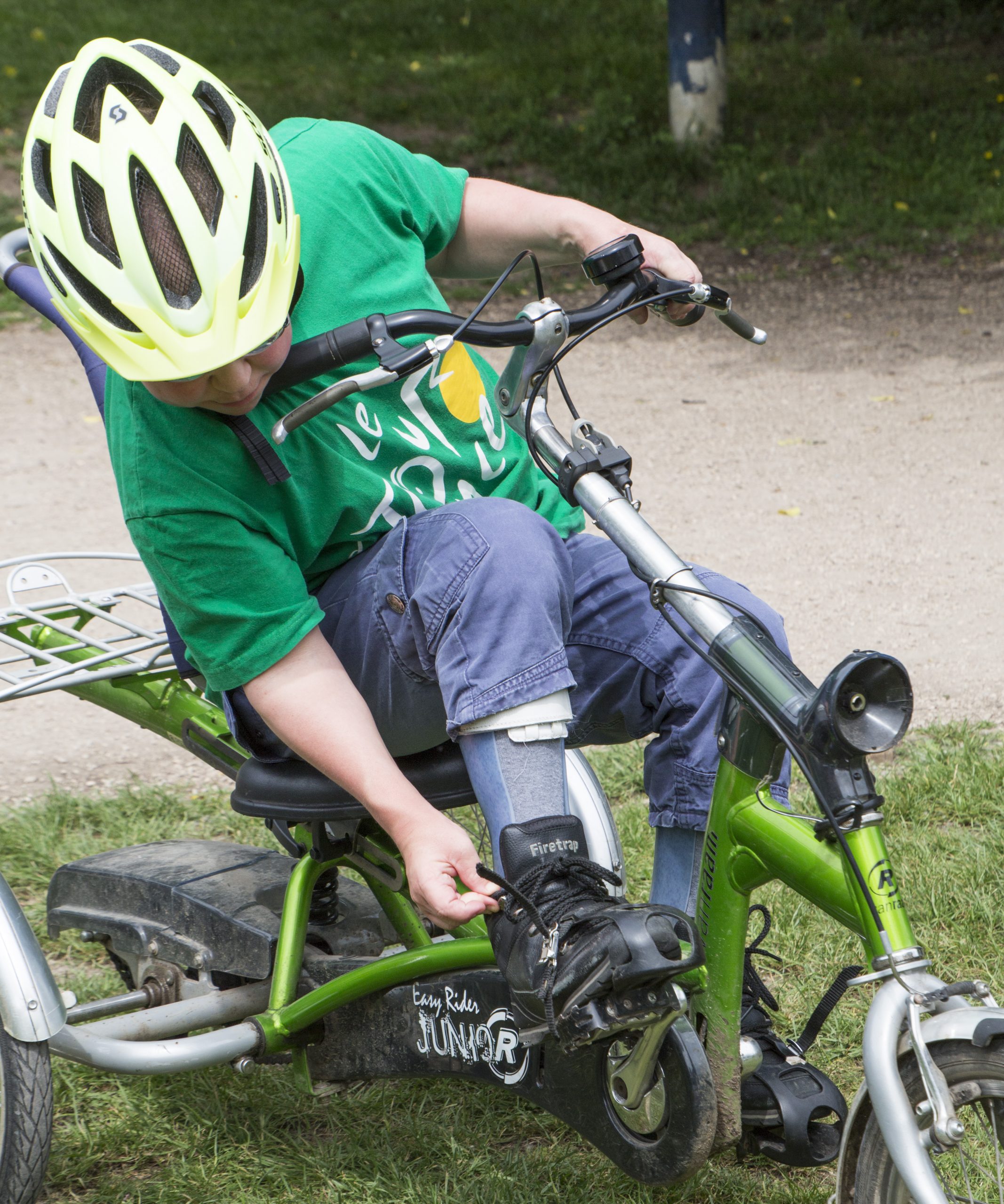 Young cyclist adjust footrests on adapted cycle