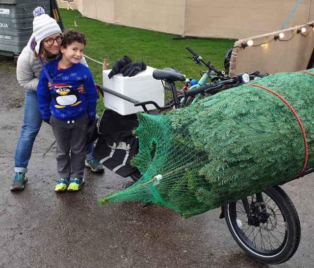 Family pose next to their Christmas they are taking home on their bike