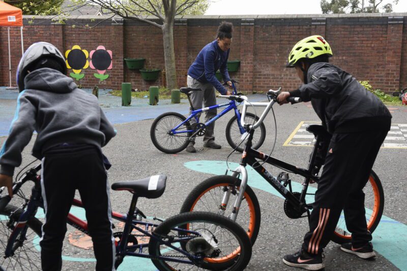 Cycle for Life Bikeability session in Liverpool, Bikeability instructor is teaching two students how to check their bikes before a ride