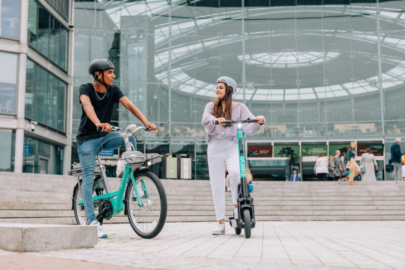 Two people using a Beryl cycle and an e-scooter