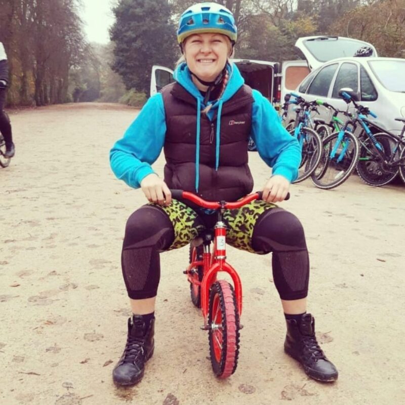 Emma smiling while sitting on a small balance bike