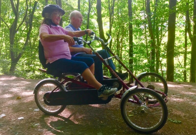 A couple using a side by side trike in the forest