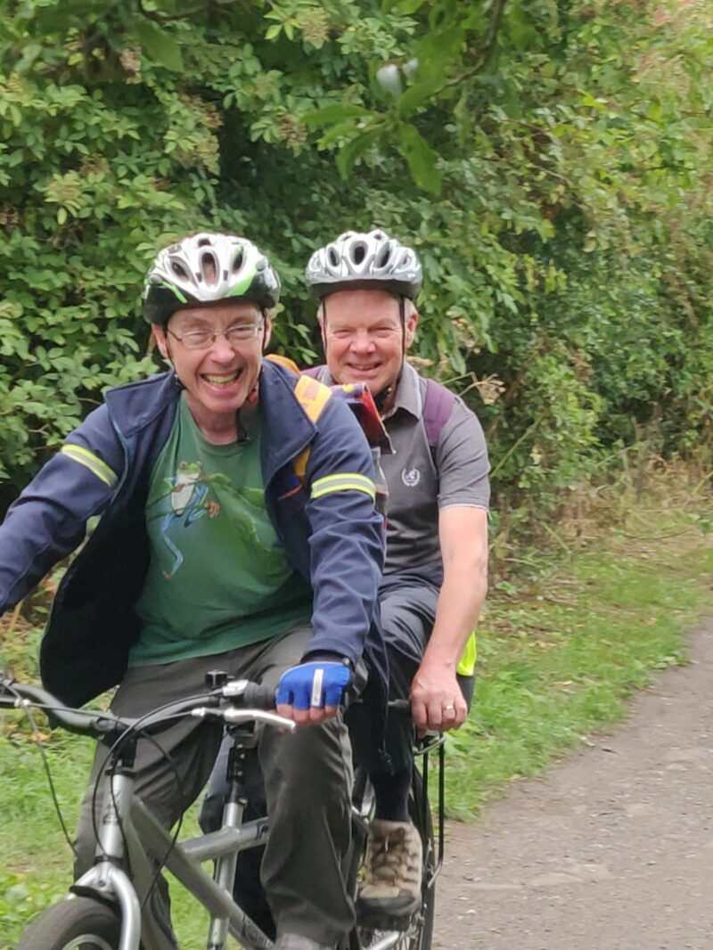 Two people using a tandem cycle in the forest