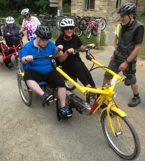 Two people using an adapted bike ready to explore the forest