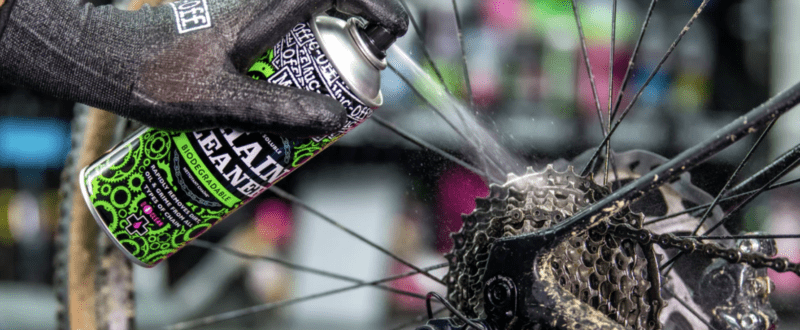 Close up of a hand spraying chain cleaner onto a cycle chain cassette