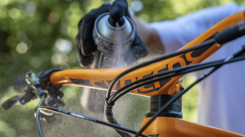 Close up of a hand spraying degreaser onto a cycle