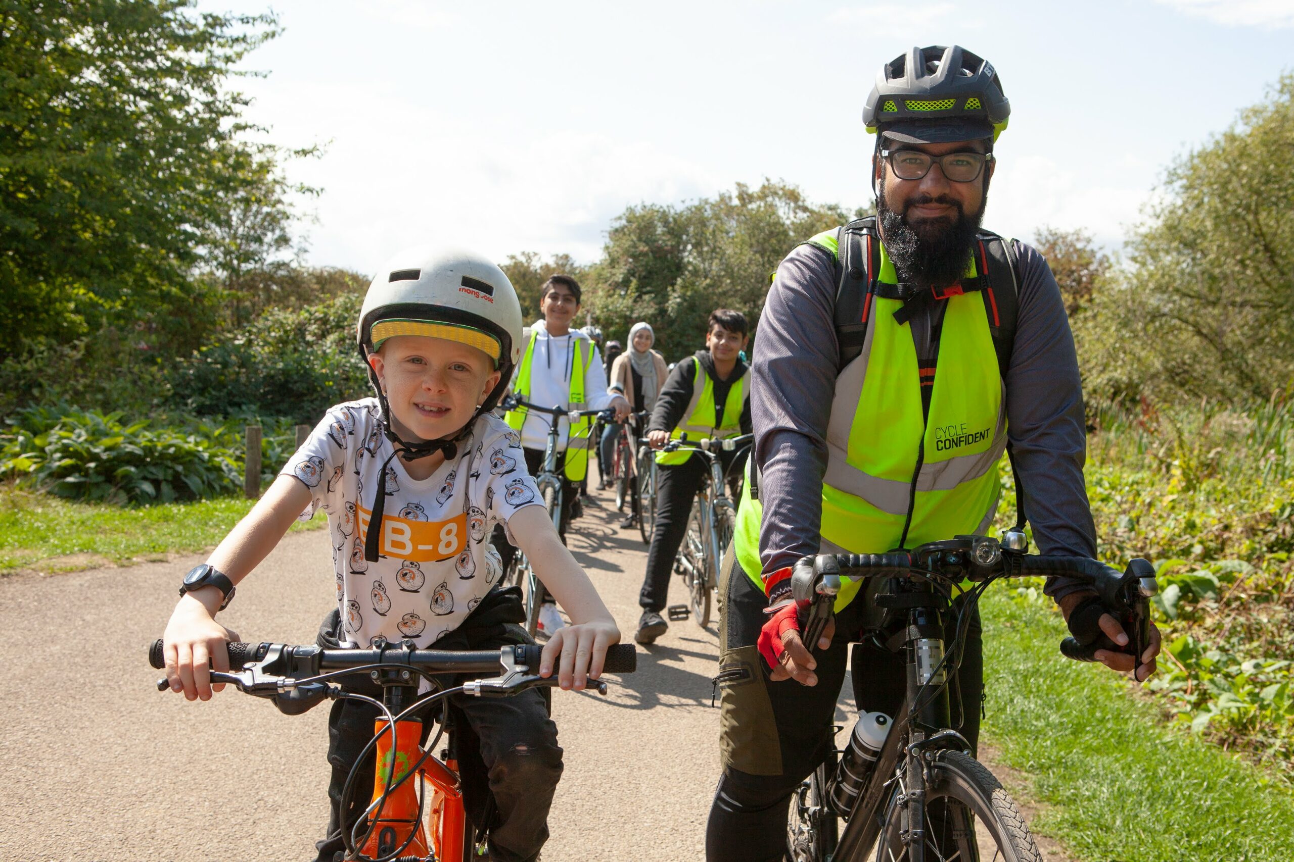 A group of men, women and children enjoying a cycle ride in a park