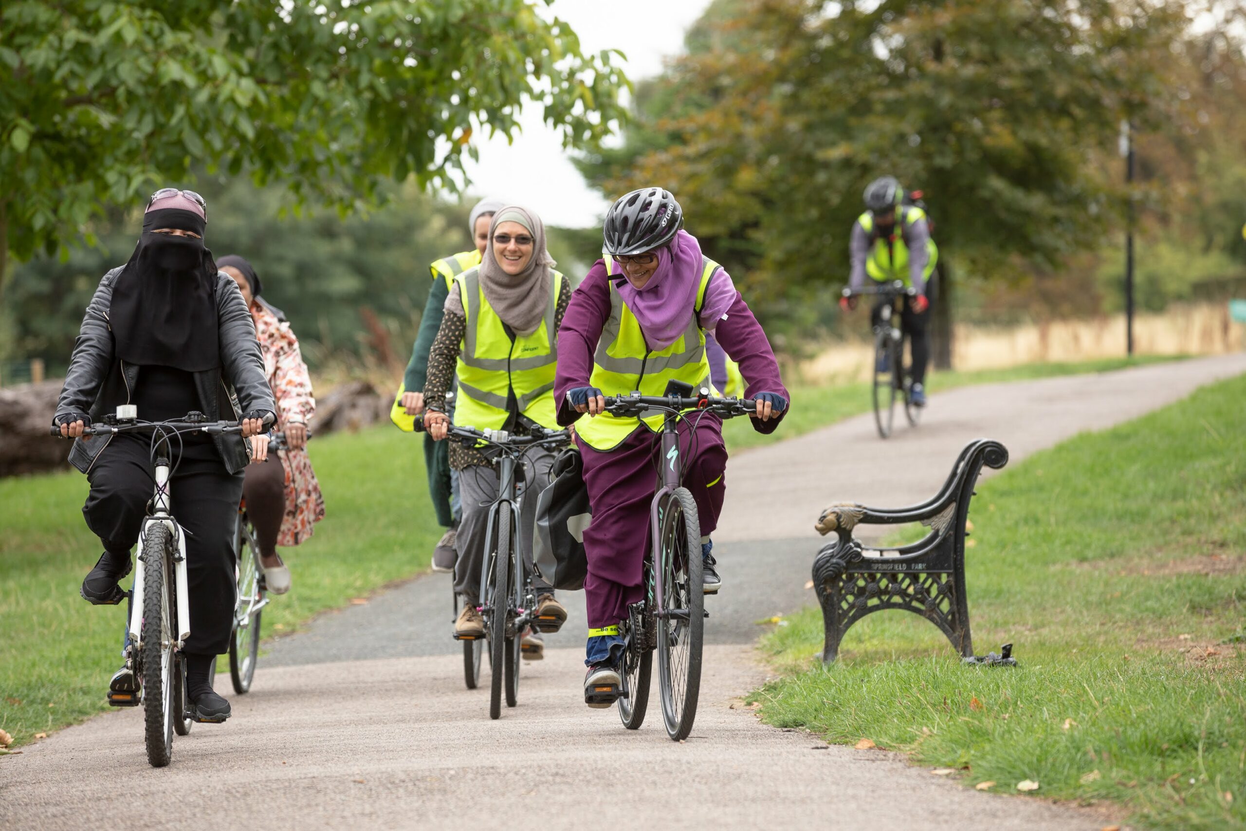 A group of women cycling in a park, wearing hijabs and other headscarves