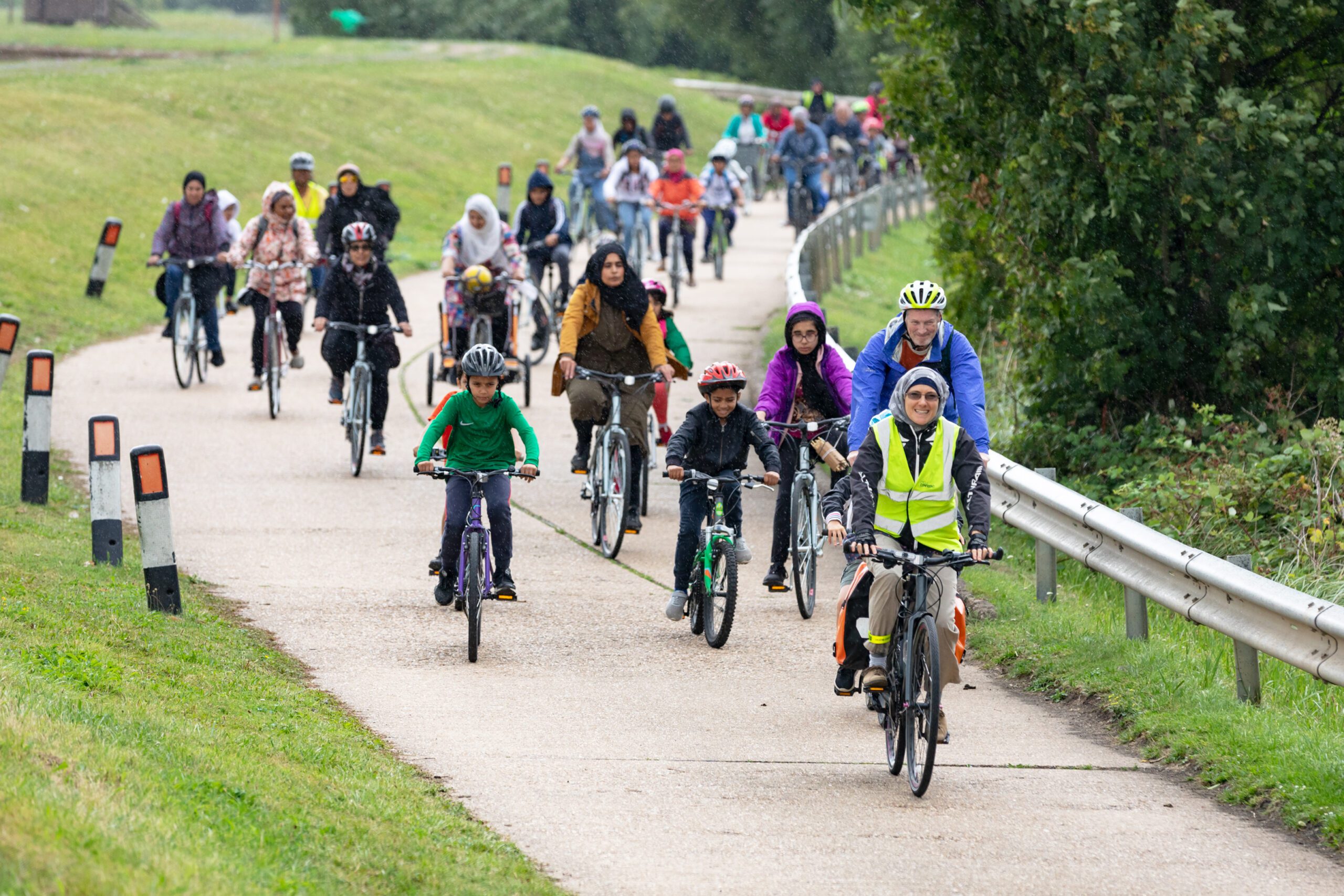 A large group of muslim men, women and children enjoying a cycle ride in a park
