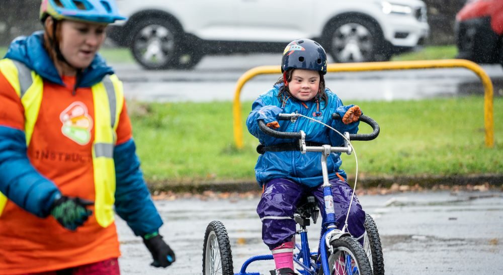 A Bikeability student on a tricycle following an instructor