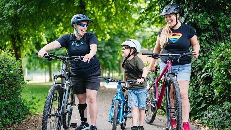 A family of 3 with their bikes laughing and smiling