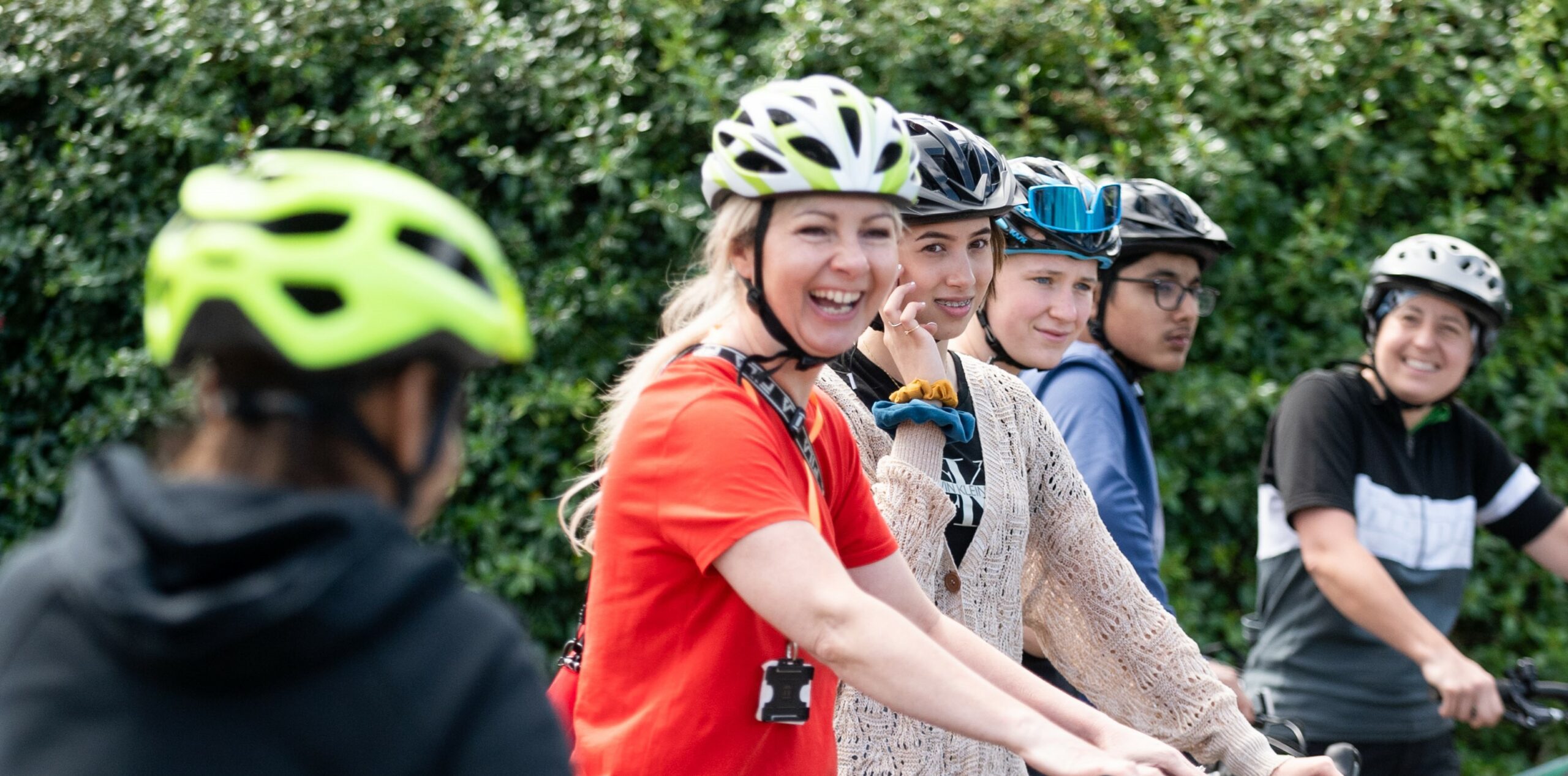 A group of people in helmets are smiling as they prepare to go on a cycle ride