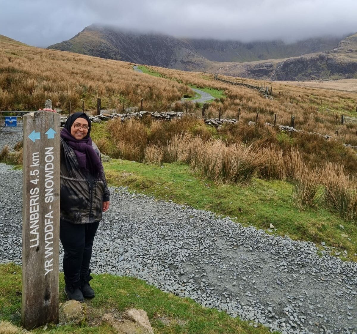 Naida standing by a waypoint on a hike in the countryside