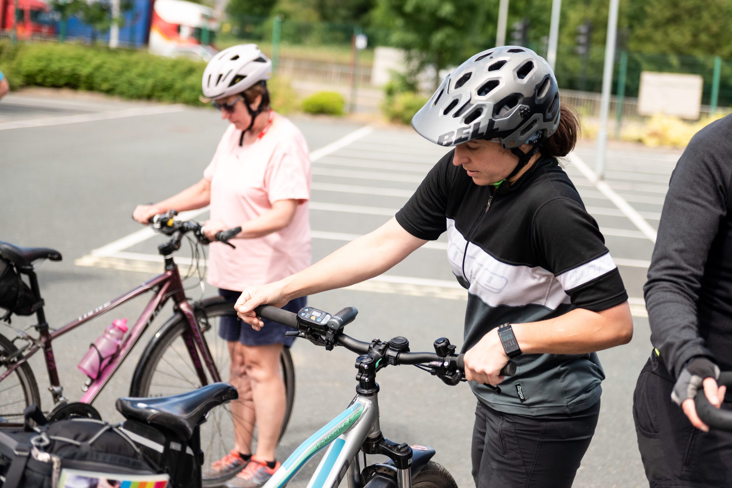 Two women wearing helmets are checking their cycles before they set off on a ride