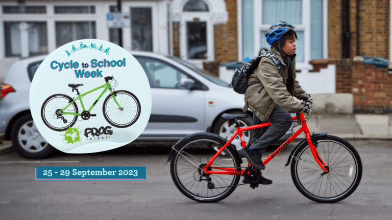A boy on a red Frog cycle. A sticker on top says Cycle to School Week and has an image of the bike that can be won