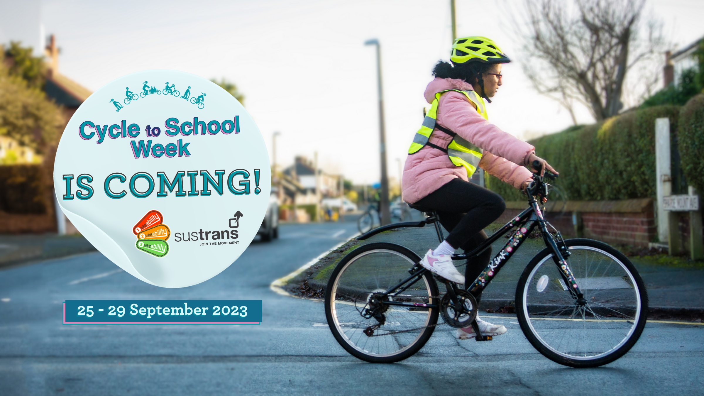 A girl in a pink coat cycling. A sticker on top says cycle to school week is coming!