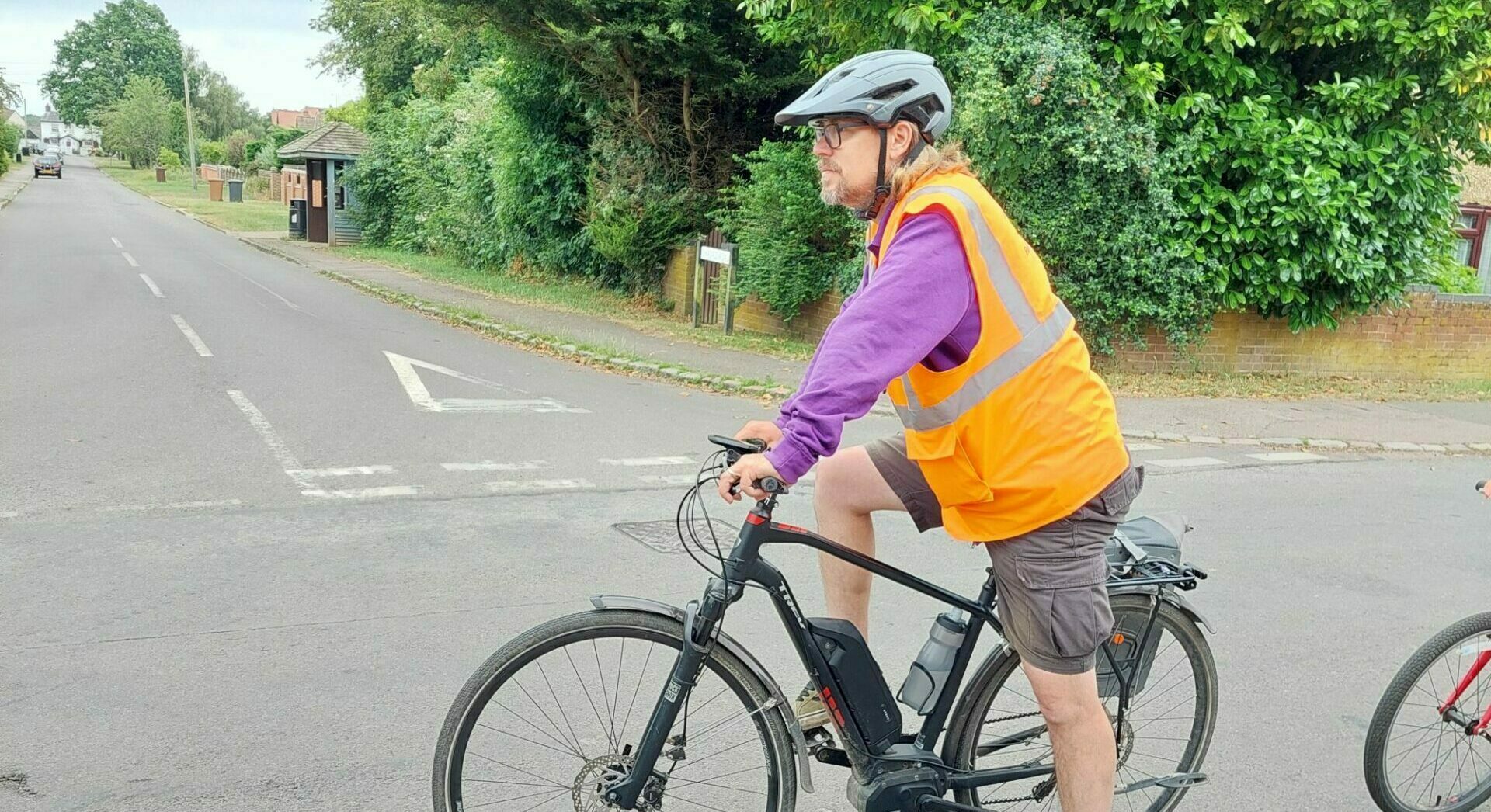 David teaching a Bikeability lesson. He is wearing a hi vis vest and waiting to make a turn