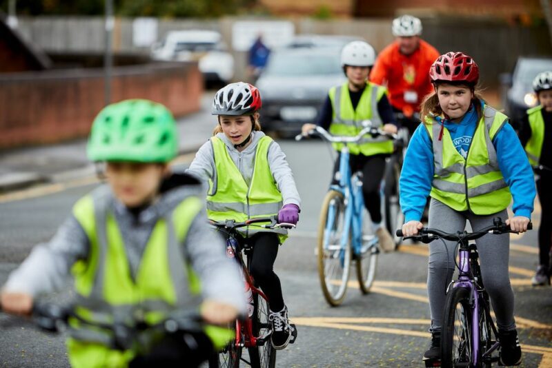 A group of children cycling on the road as part of their Bikeability lesson.