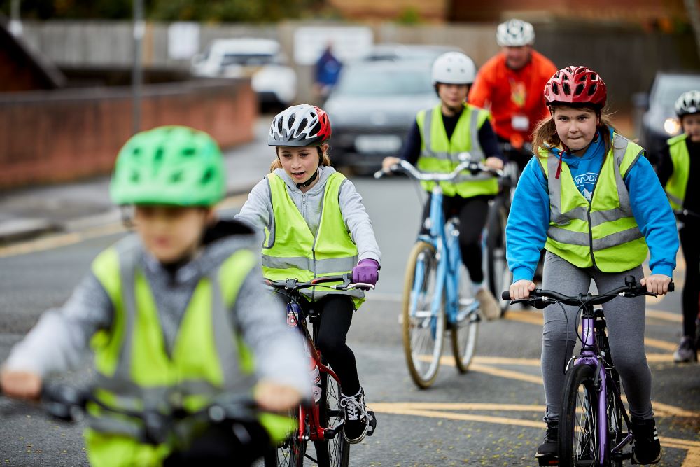 A group of children cycling on the road as part of their Bikeability lesson.