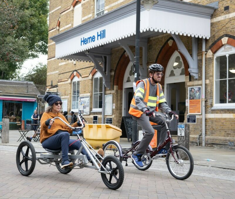 Two cyclists riding tricycles