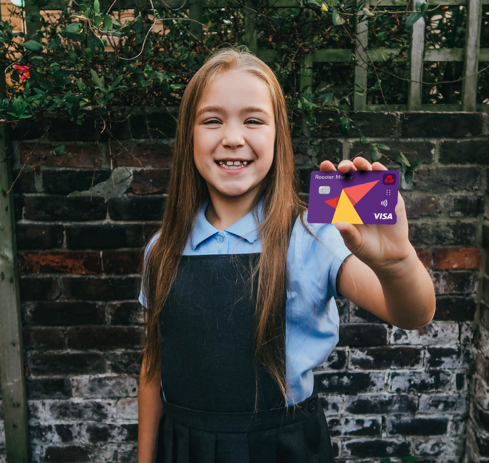 A girl in a school uniform is smiling and holding up a rooster money card