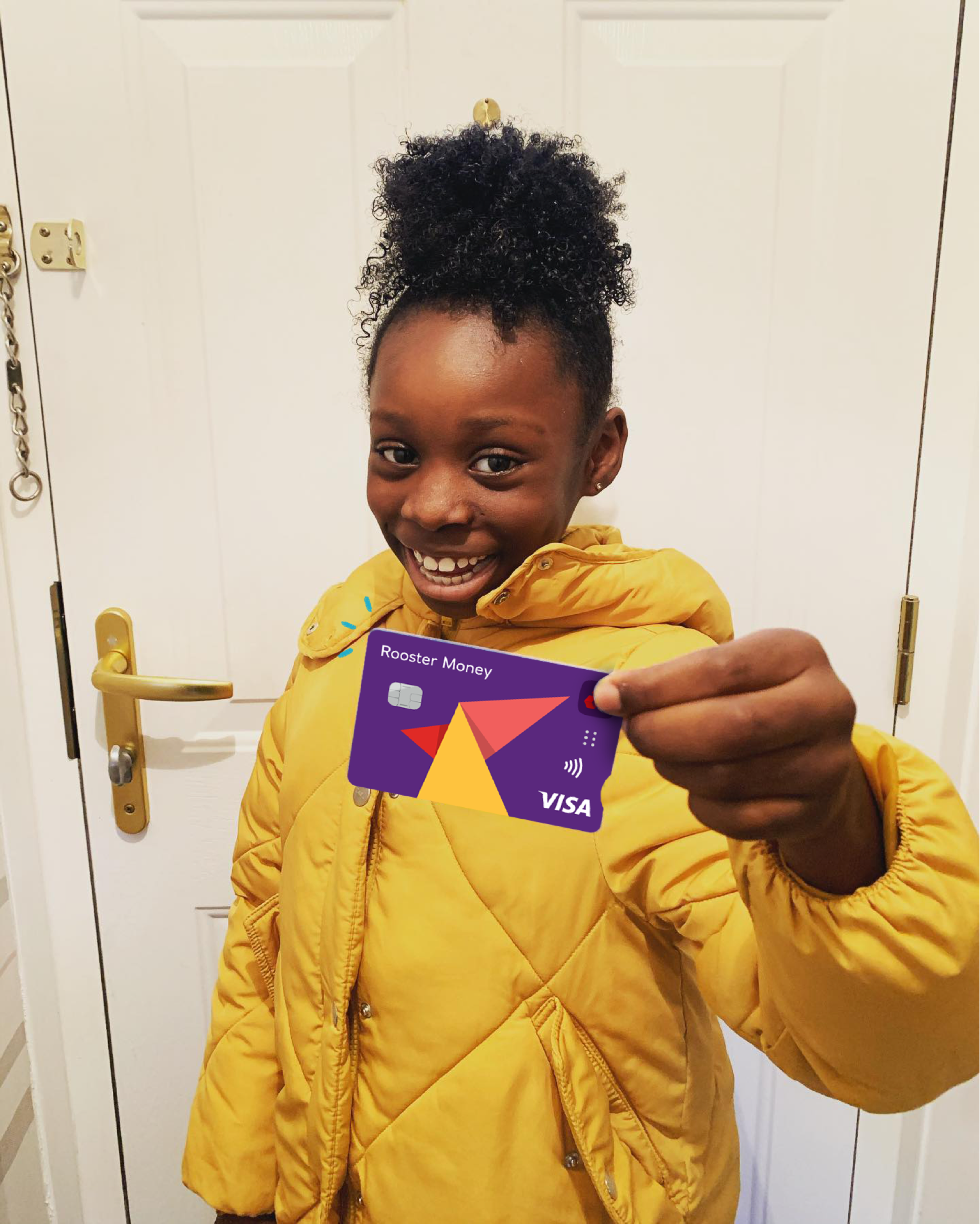 A girl wearing a yellow puffer jacket is smiling and holding up a rooster money card